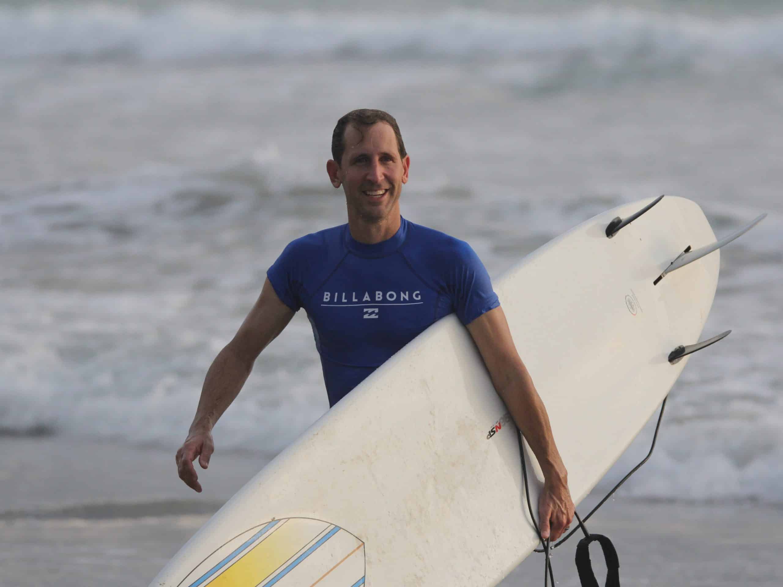 Steve Welch holding a surfboard at the beach